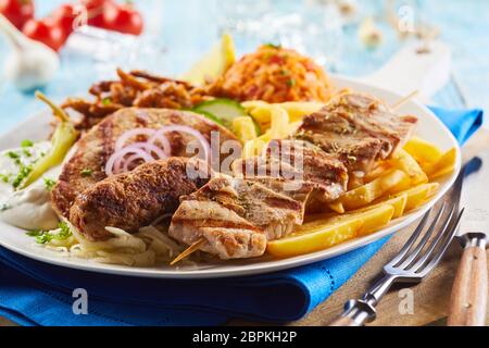 Gegrilltes Fleisch sortiert auf einer Platte mit gebratenen Pommes, Reis, Salat und Zwiebeln für einen leckeren griechischen Abendessen in der Nähe zu sehen. Stockfoto