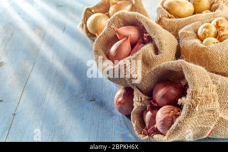 Rustikale Ernte Konzept mit sack Taschen mit verschiedenen Arten von frischem Zwiebel von lokalen Markt, auf Holz- Oberfläche mit Kopie Raum platziert Stockfoto