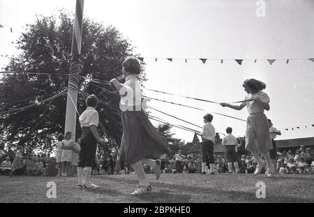 1980er Jahre, historische, junge Kinder tanzen um die Maibaum auf dem Dorfgrün in Poppleton, West Yorkshire, England, Großbritannien, eine traditionelle Aktivität auf dem Frühjahrstag Mai Feiertag. Stockfoto