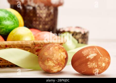 Stillleben mit farbigen ostereiern und osterkuchen auf einem Holztisch auf hellem Hintergrund. Grußkarte. Selektiver Fokus auf Eier Stockfoto