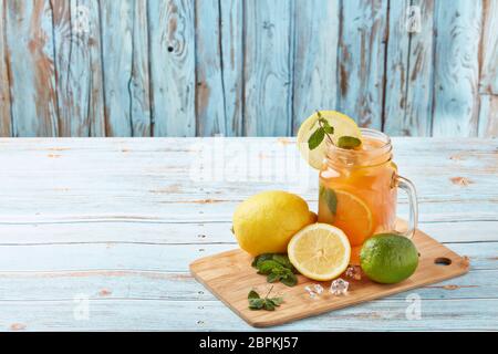 Zitruslimonade mit Eis, Minzblättern, Zitronen- und Limettenscheiben stehen auf einem blauen Holztisch. Hausgemachte Limonade mit Zitrusfrüchten. Gesundes kühles Getränk Stockfoto
