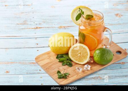 Zitruslimonade mit Eis, Minzblättern, Zitronen- und Limettenscheiben stehen auf einem blauen Holztisch. Hausgemachte Limonade mit Zitrusfrüchten. Gesundes kühles Getränk Stockfoto