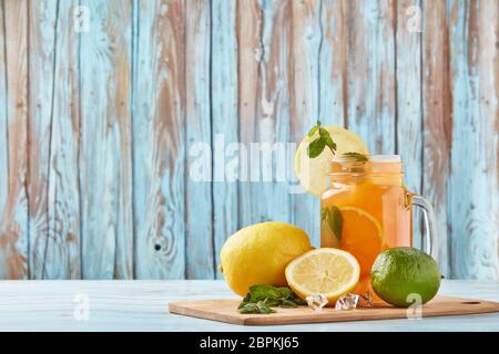 Zitruslimonade mit Eis, Minzblättern, Zitronen- und Limettenscheiben stehen auf einem blauen Holztisch. Hausgemachte Limonade mit Zitrusfrüchten. Gesundes kühles Getränk Stockfoto