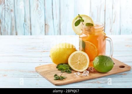 Zitruslimonade mit Eis, Minzblättern, Zitronen- und Limettenscheiben stehen auf einem blauen Holztisch. Hausgemachte Limonade mit Zitrusfrüchten. Gesundes kühles Getränk Stockfoto
