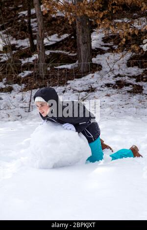 Junge Mädchen bilden ein Schneemann an einem sonnigen Tag im Winter verschneite Wälder in den Bergen. Stockfoto