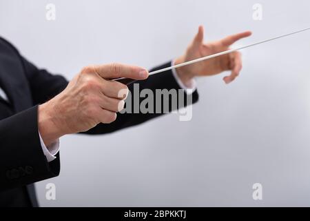 Nahaufnahme einer Musik Dirigent Hände halten Baton gegen grauer Hintergrund Stockfoto