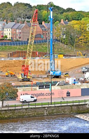 Baustellen-Fundament, das schwere Maschinen und Anlagen stapelt, neue Immobilienentwicklung neben River Wear vor Wohnhäusern in Durham UK Stockfoto