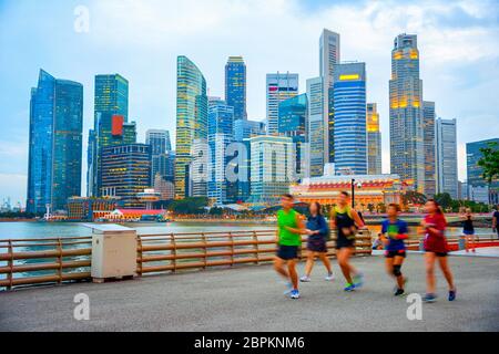 Menschen joggen in Singapur Damm, Abend City Skyline im Hintergrund Stockfoto