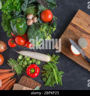 Gesunde Gemüseauswahl mit rustikalem Schneidebrett auf Schieferplatte Stockfoto