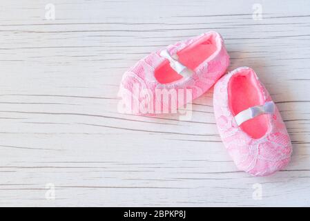 Kleine rosa Schuhe auf weißem Holzhintergrund. Wartender Baby, Babydusche. Rosa Mädchen Neugeborenen Schuhe. Mode und Kleidung für Baby Konzept. Stockfoto