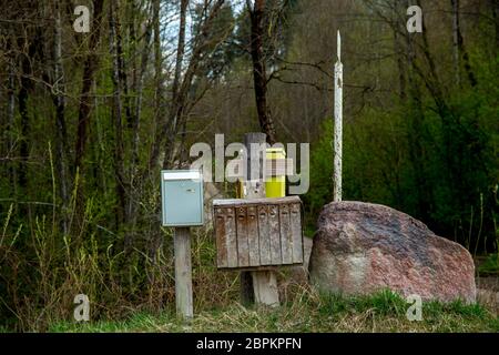 Frühling Landschaft mit ländlichen Mailbox. Alte Mailbox im ländlichen am Straßenrand neben dem großen Stein in Lettland. Stockfoto