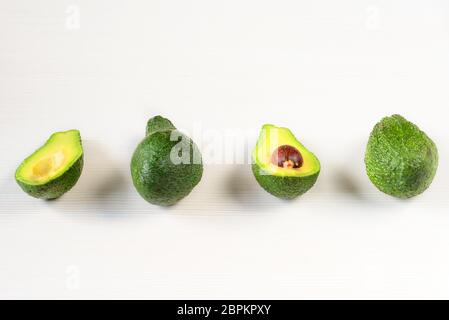 Isolierte Avocado. Ganze Avocado Früchte und zwei Hälften in einer Reihe auf weißem Hintergrund mit Schnittpfad isoliert Stockfoto