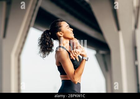 Seitenansicht einer Fitness-Frau, die Arme Stretching Übung unter Autobahn im Freien Stockfoto