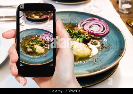 Travel Concept - Besucher Fotos von Traditionelle kaukasische Suppe Putuk (Piti) von Hammel Brust, Kichererbsen, Kartoffeln in der Platte auf dem Smartphone Stockfoto