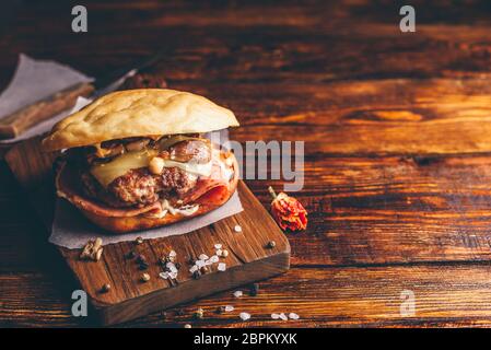 Hausgemachten Burger auf Schneidebrett. Cheeseburger mit Rindfleisch Patty, Wisconsin Schweizer Käse, Schinken, sautierten Champignons, Dijon Senf, Mayonnaise und Kartoffel R Stockfoto