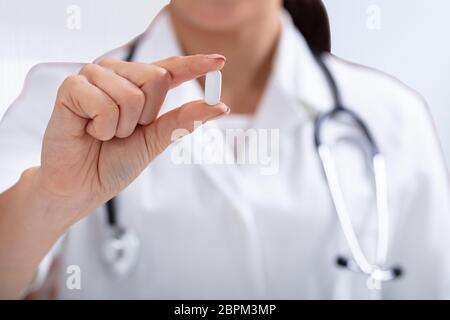 In der Nähe der weiblichen Doktor mit Stethoskop um den Hals halten weiße Tablette in der Hand Stockfoto