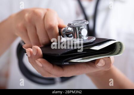 In der Nähe von einem Arzt Hand Prüfung Geldbörse mit Stethoskop Stockfoto