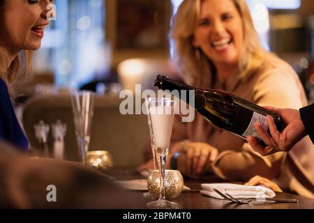 Nahaufnahme einer unkenntlich Kellner ein Glas Prosecco zu gießen. Stockfoto