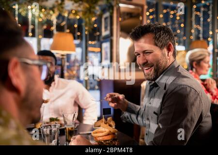 Kleine Gruppe von Mitte der erwachsenen männlichen Freunde genießen einige Essen in einem Restaurant. Sie reden und genießen jede andere Firma. Stockfoto