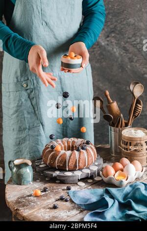 Weibliche Hände gießen Beeren auf ostern Hefe Kuchen auf Holzplatte Stockfoto