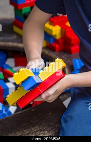 Nahaufnahme der Kinderhände mit bunten Plastikziegeln und Details von Spielzeug. Junge spielen mit Teilen von hellen kleinen Ersatzteilen von lego. Stockfoto