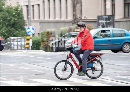 Belgrad, Serbien - 15. Mai 2020: Älterer Mann mit grauem Bart fährt ein rotes Fahrrad im Stadtverkehr Stockfoto