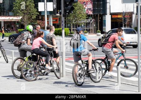 Belgrad, Serbien - 5. Mai 2020: Jugendliche Jungen und Mädchen fahren auf der Stadtstraße Fahrrad und überqueren die Straße an der Fußgängerkreuzung Stockfoto