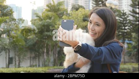 Frau, die Selfie auf dem Handy mit ihrem Hund nimmt Stockfoto