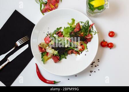 Roastbeef mit Salatmischung. Mischung aus Salaten, Kirschtomaten, gebackenem Pfeffer, getrockneten Tomaten, Roastbeef, Senfsoße Stockfoto