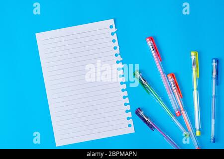 Leere Blatt Papier in einer Linie und mehrfarbige Gelschreiber auf einem blauen Hintergrund Stockfoto