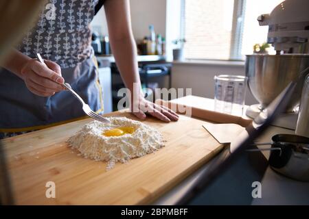 Anonyme Person, die frische Pasta zu Hause in der Küche, ein Video-Rezept mit Eiern und Mehl. Stockfoto