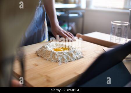 Anonyme Person, die frische Pasta zu Hause in der Küche, ein Video-Rezept mit Eiern und Mehl. Stockfoto