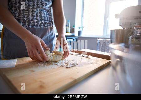 Frau macht frischen Teig zu Hause in ihrer Küche, kneed und Mischen der auf Holzbrett. Stockfoto