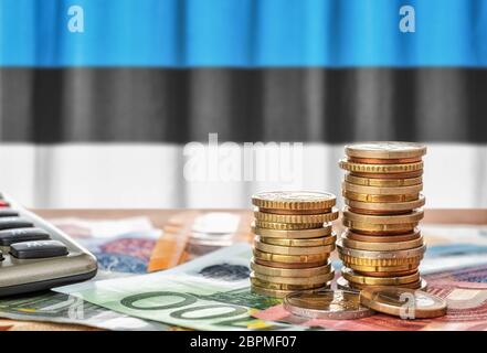 Euro-Banknoten und -Münzen vor der estnischen Nationalflagge Stockfoto