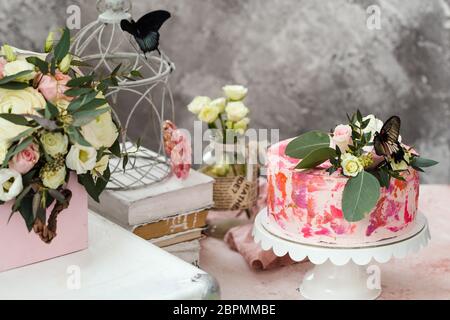 Rosa Kuchen mit Blumen und echten Schmetterlingen rosa romantische Atmosphäre dekoriert Stockfoto