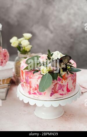 Rosa Kuchen mit Blumen und echten Schmetterlingen rosa romantische Atmosphäre dekoriert Stockfoto