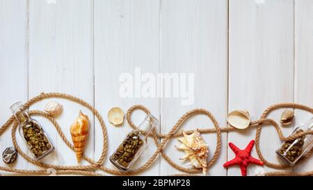 Sommer-Innenausstattung mit Seesternen, Muscheln, Seilen und Flaschen mit Steinen auf weißem Holzhintergrund. Kopierbereich. Stillleben. Flaches Lay Stockfoto