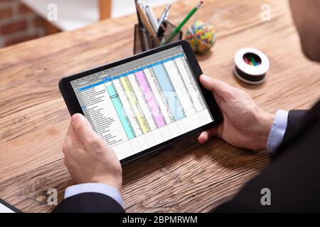 Ansicht der Geschäftsmann Hand Analyse der Daten über digitale Tablet über Schreibtisch Stockfoto
