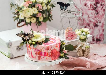 Rosa Kuchen mit Blumen und echten Schmetterlingen rosa romantische Atmosphäre dekoriert Stockfoto