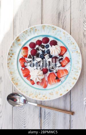 Haferbrei Porrige mit Milch, frischen Erdbeeren, Heidelbeeren und Himbeeren. Draufsicht, Holzhintergrund. Stockfoto