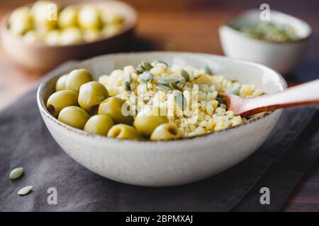 Bulgur mit grünen Oliven und Pepitas, gesunde Ernährung einfach Rezept aus lange gelagerten Lebensmitteln. Stockfoto