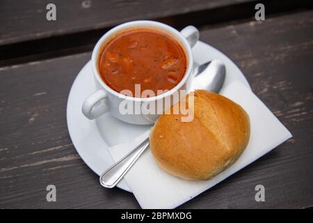 Soljanka mit Brötchen und Löffel auf einem Tisch Stockfoto