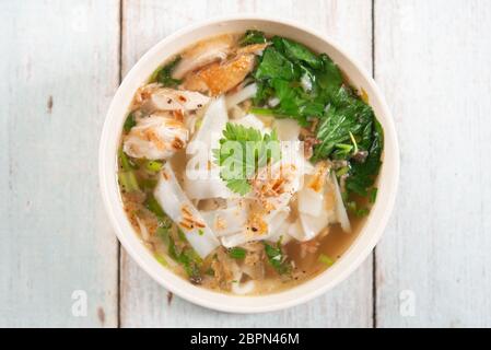 Asiatische Kway Teow Suppe, Nudeln und Huhn in Schüssel auf Holz- Hintergrund. Ansicht von oben flach. Stockfoto