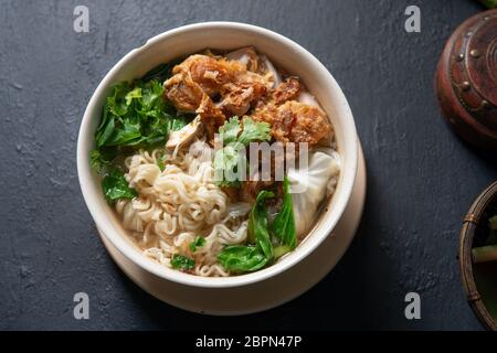 Asiatische Ramen Nudeln Suppe und Hühnchen in der Schüssel auf dunklem Hintergrund. Ansicht von oben flach. Stockfoto