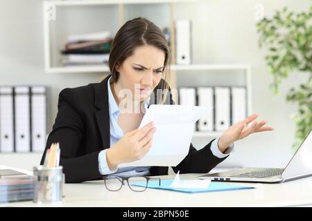 Verwirrt Büroangestellter Lesen von Dokumenten auf einem Desktop Stockfoto