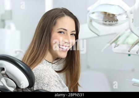 Zufrieden Zahnarzt Patienten zeigen ihr perfektes Lächeln nach der Behandlung in einer Klinik-Box mit medizinischen Geräten im Hintergrund Stockfoto