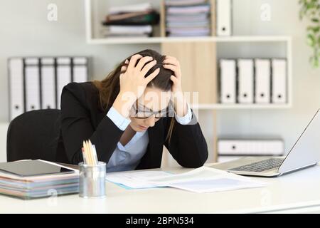 Deprimiert Büroangestellter lesen Sales Reports auf einem Desktop Stockfoto