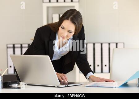 Busy Geschäftsfrau arbeiten Vergleichen von Dokumenten online mit einem Laptop im Büro Stockfoto