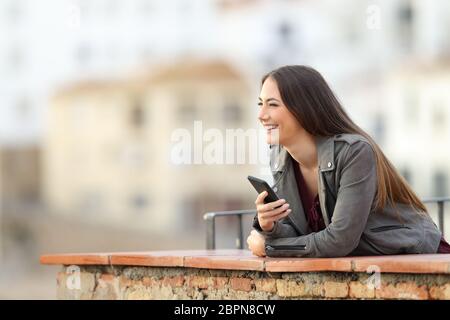 Happy woman holding Smart Phone, die Landschaft draußen in einer Stadt Stadtrand Stockfoto