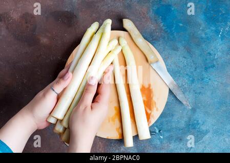 Bunche von hausgemachten frischen Bio-weißen Spargel in den Händen einer Frau über Holzbrett zum Kochen vegetarisch gesunde Lebensmittel auf einem dunklen Beton backgr Stockfoto